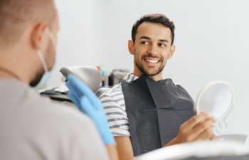 A dentist and a happy male patient after restorative treatment.